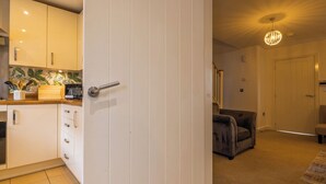 A modern kitchen with white cabinets, a wooden countertop, and a tiled backsplash. - E-Solace-  Etihad-Coop LIVE-Free Parking-Pool Table (Manchester)