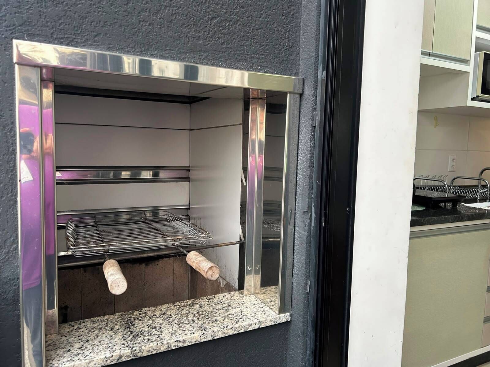 A kitchen with a built-in stainless steel oven, a granite countertop, and a hanging rack.