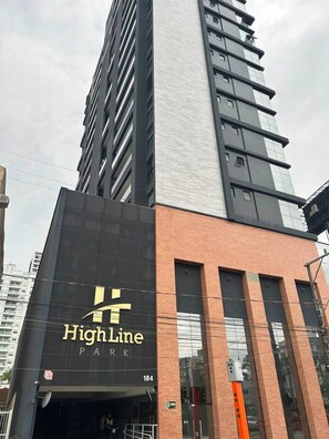 Un edificio con un llamativo letrero que dice 'High Line Park' en la fachada, indicando un parque contiguo al edificio.