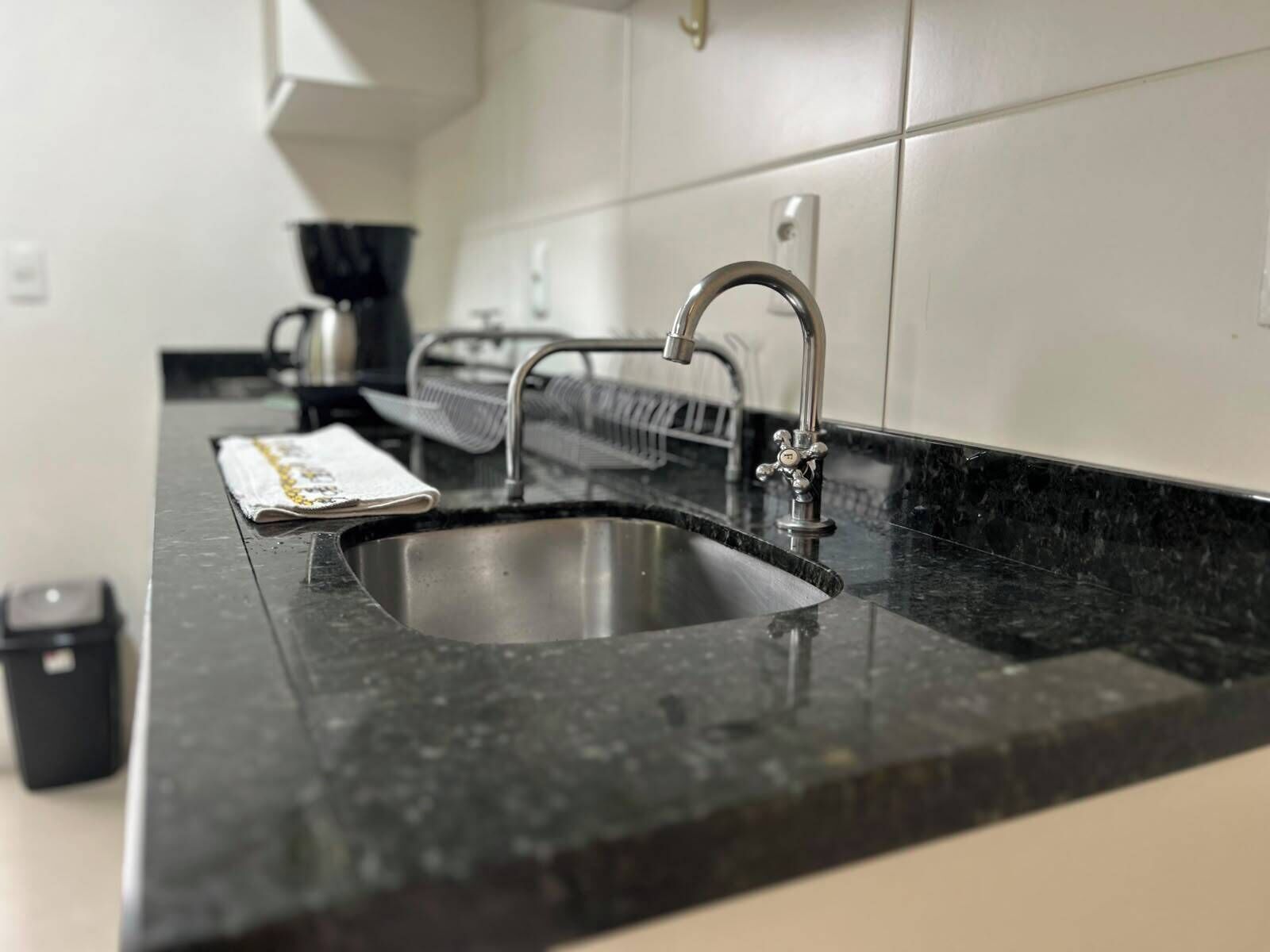 A modern kitchen with a black granite countertop, stainless steel sink, and a dish rack.