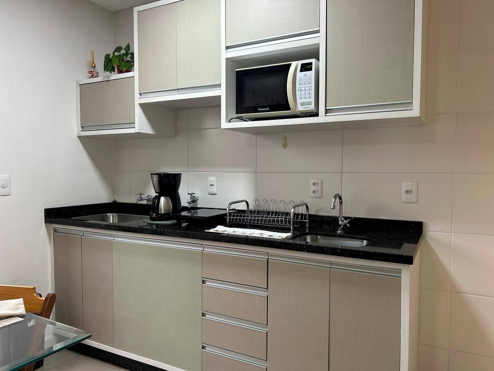 Una cocina moderna con microondas integrado, cafetera y escurreplatos.
