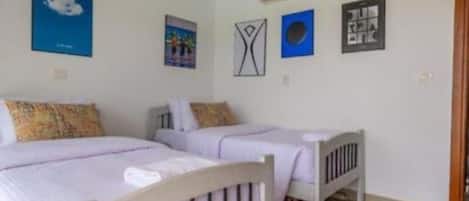 A bedroom with two beds, a rug, and wall art.