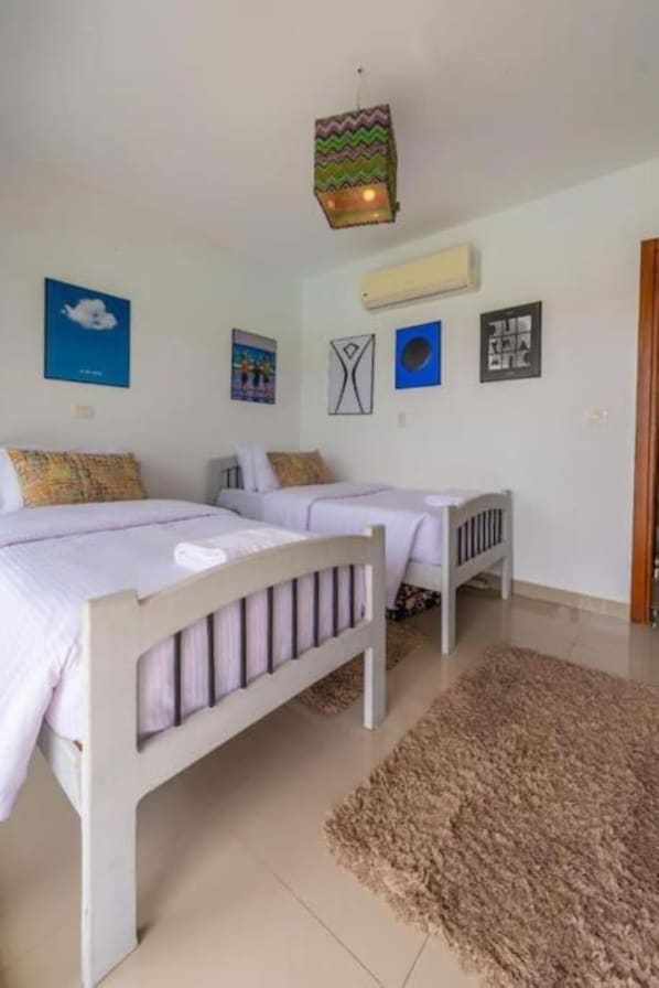 A bedroom with two beds, a rug, and wall art.