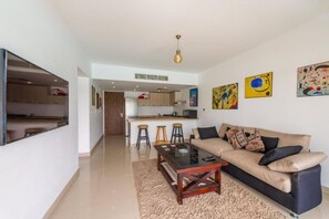 A modern living room with a sofa, coffee table, and a kitchen in the background.