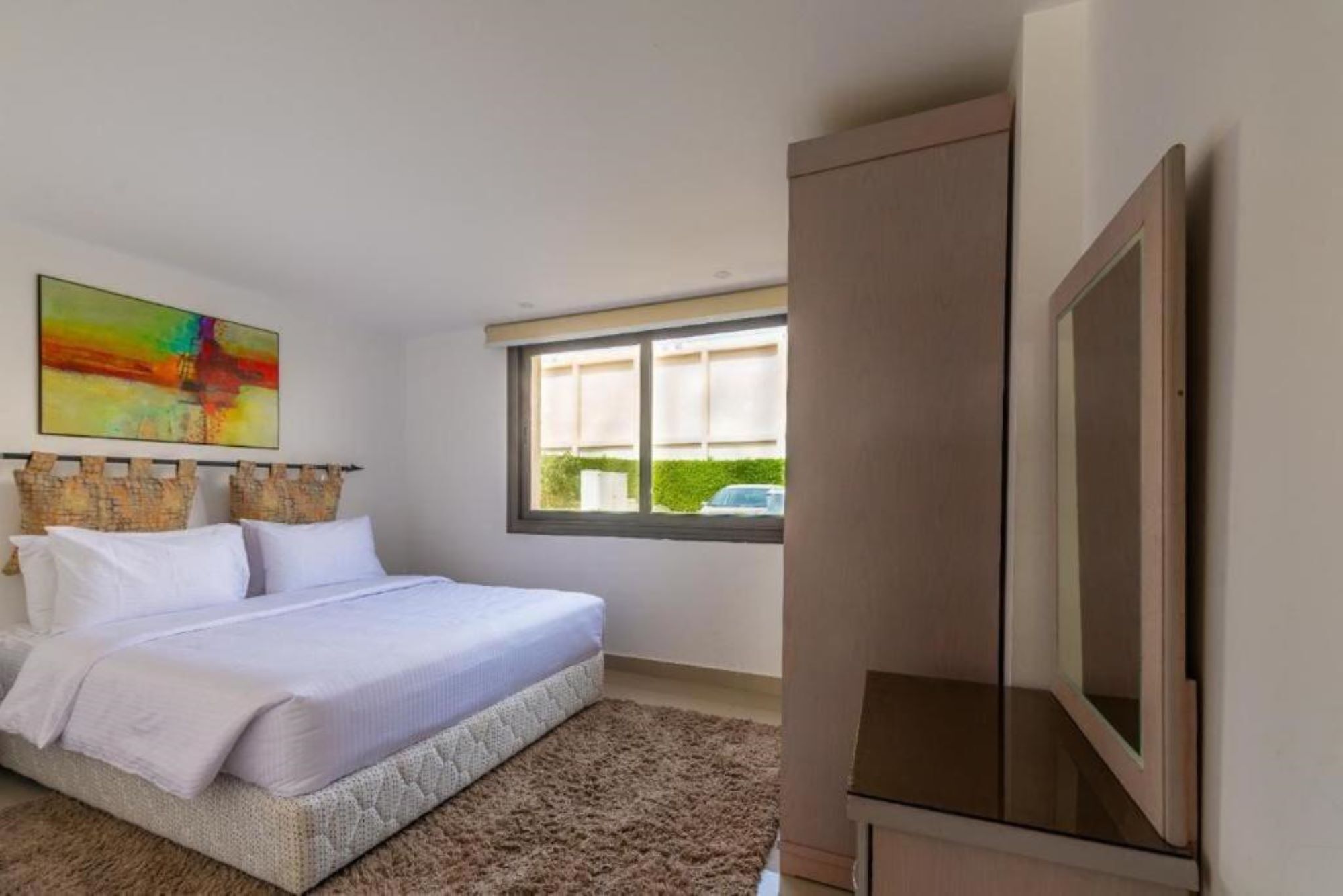 Une chambre à coucher avec un lit, une fenêtre, un tableau et une armoire.