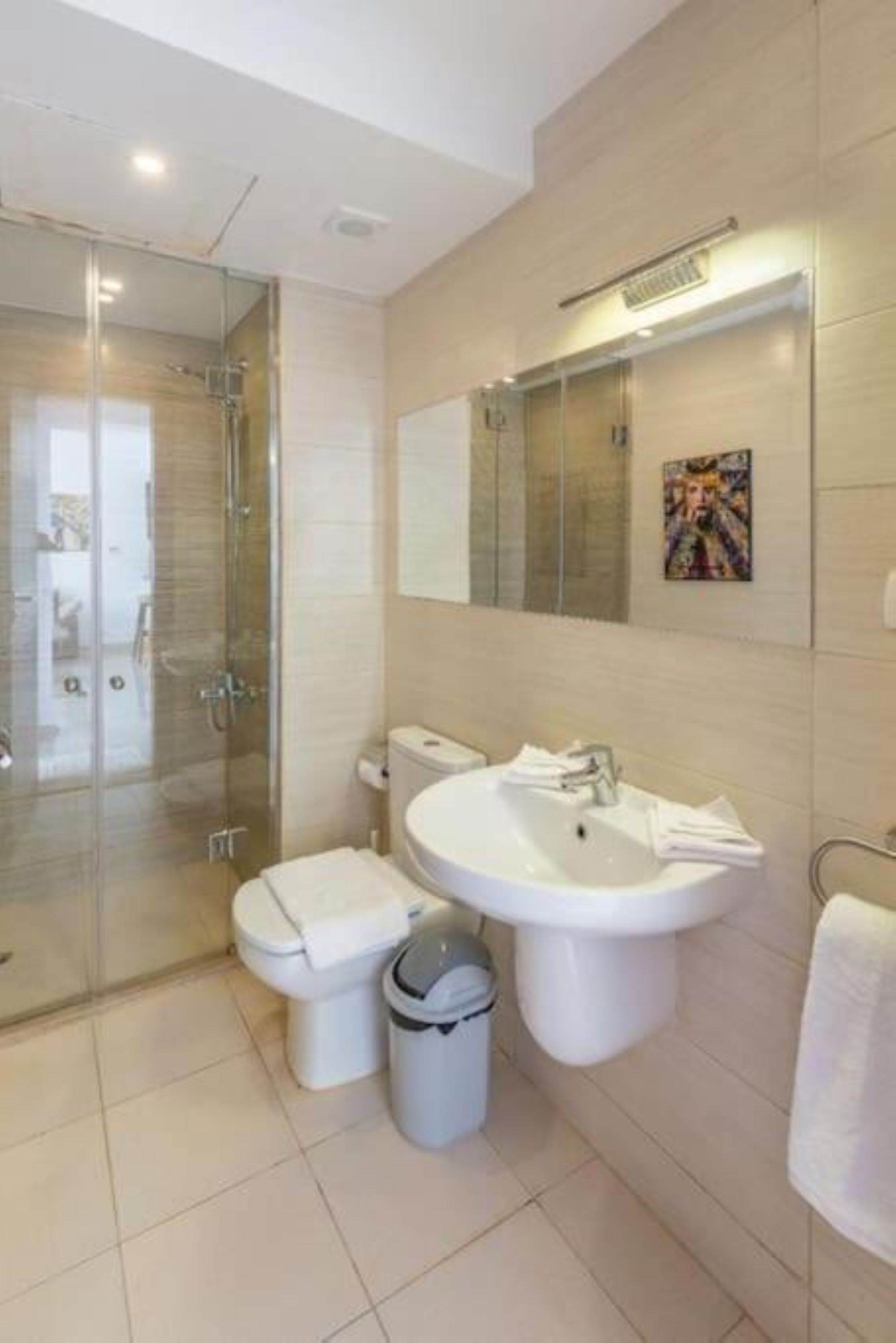 Une salle de bain moderne avec une douche à parois de verre, des toilettes, un lavabo et une poubelle.