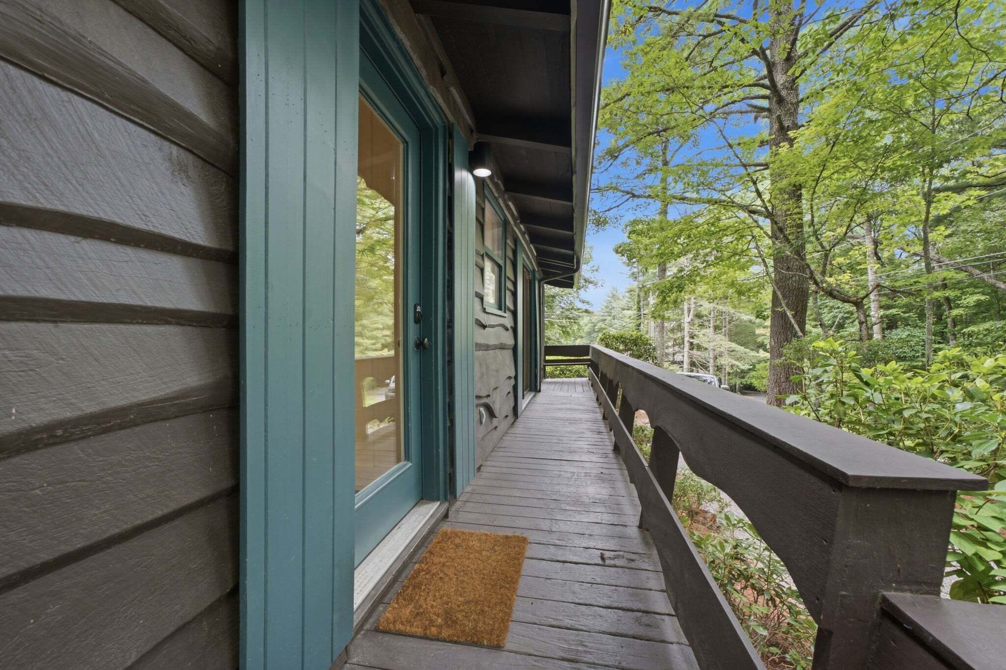 A wooden porch with a view of a forested area.