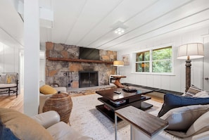 A modern living room with a stone fireplace, a large window, and a cozy seating area. - Hemlock Cottage, 3/3 close to downtown (Highlands)