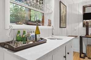 A kitchen with a white countertop, a wine bottle, and several bottles of water. - Hemlock Cottage, 3/3 close to downtown (Highlands)