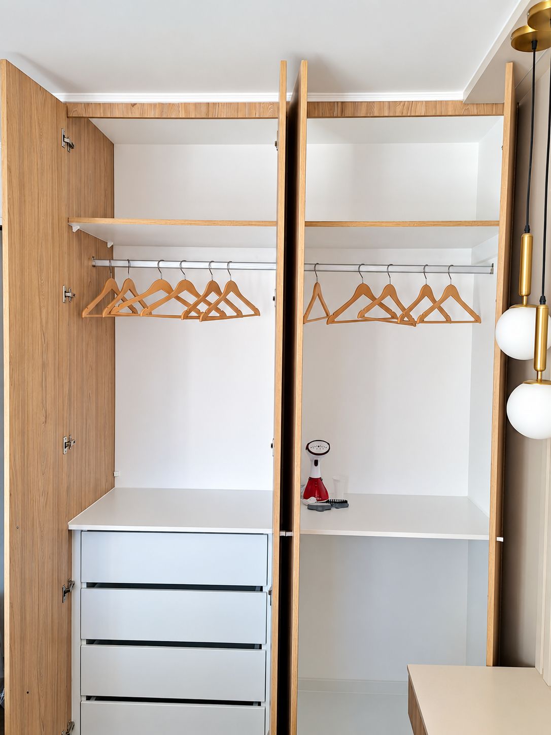 Un closet espacioso con puertas de madera, barra para colgar ropa y un mueble con cajones.