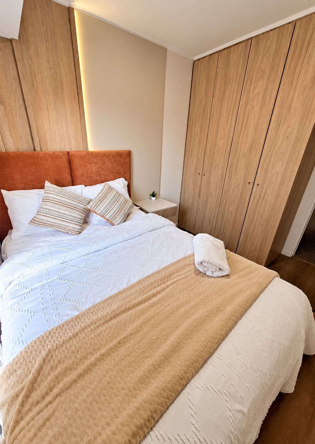 A neatly made bed with a headboard, pillows, and a blanket.