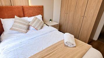 A neatly made bed with a headboard, pillows, and a blanket.