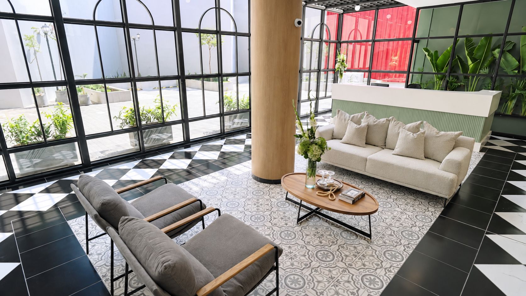Un'accogliente hall d'albergo con pavimento a scacchi, un divano, un tavolino da caffè e la reception.