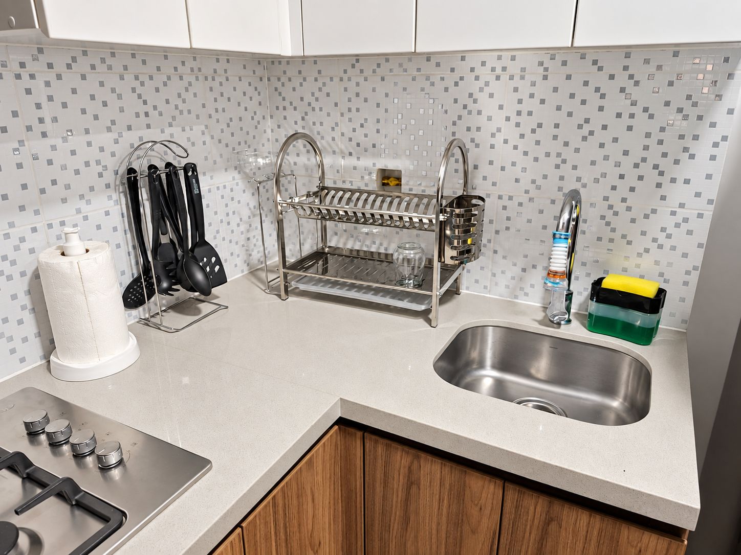 A kitchen with a stainless steel sink, a dish rack, and a stove.