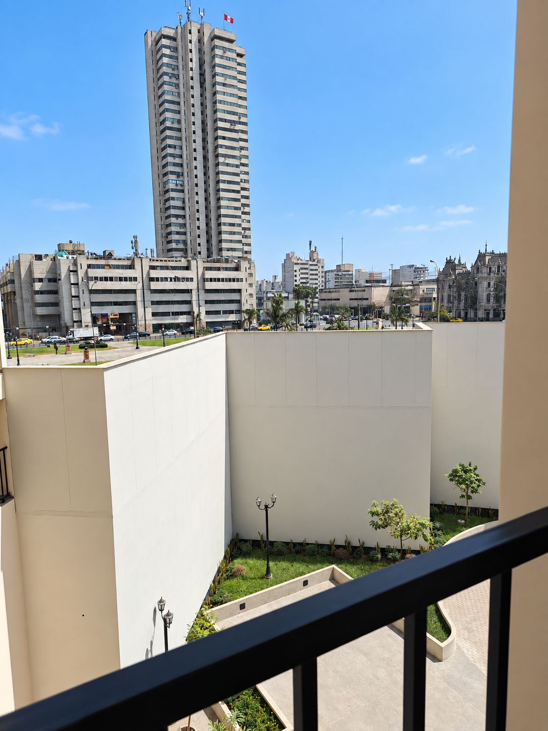 A high-rise building with a Canadian flag, surrounded by other buildings and a clear sky.
