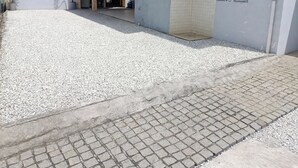 Um edifício com um caminho de cascalho que leva a uma entrada pavimentada.