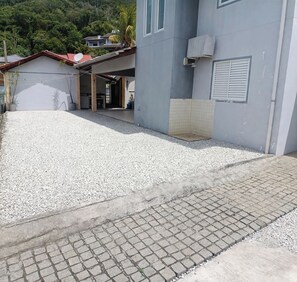 A building with a gravel driveway leading to a paved entrance. - 4-bedroom house 200 meters from Canto Grande beach, pets allowed. (Bombinhas)