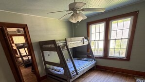 A room with a bunk bed, a ceiling fan, and a window with blinds.