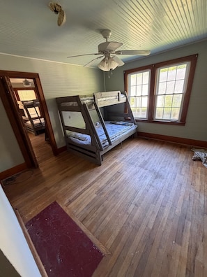 A room with a bunk bed, a ceiling fan, and a window with blinds.
