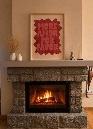 A fireplace with a stone surround, a framed sign above it, and a small decorative arrangement on the mantel.