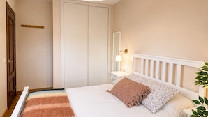 A bedroom with a bed, bedside table, lamp, and a hanging light fixture.