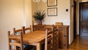 A dining area with a wooden table and chairs, a chandelier, framed artwork, and a potted plant.
