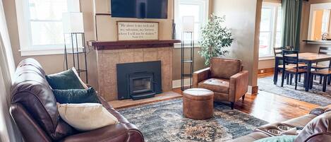 Una sala de estar con sofás de cuero, una chimenea, un televisor y un comedor.