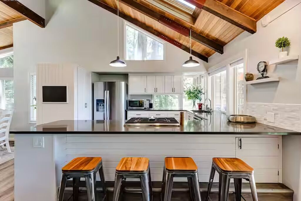 Una cocina moderna con una isla grande, taburetes de bar e iluminación colgante.