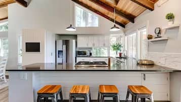 Una cocina moderna con una isla grande, taburetes de bar e iluminación colgante.