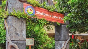 Ein steiner Torbogen mit einem Schild, auf dem 'Sheldon's Super Putt' steht, der zu einem Weg führt.