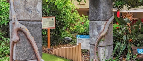 Ein steiner Torbogen mit einem Schild, auf dem 'Sheldon's Super Putt' steht, der zu einem Weg führt.