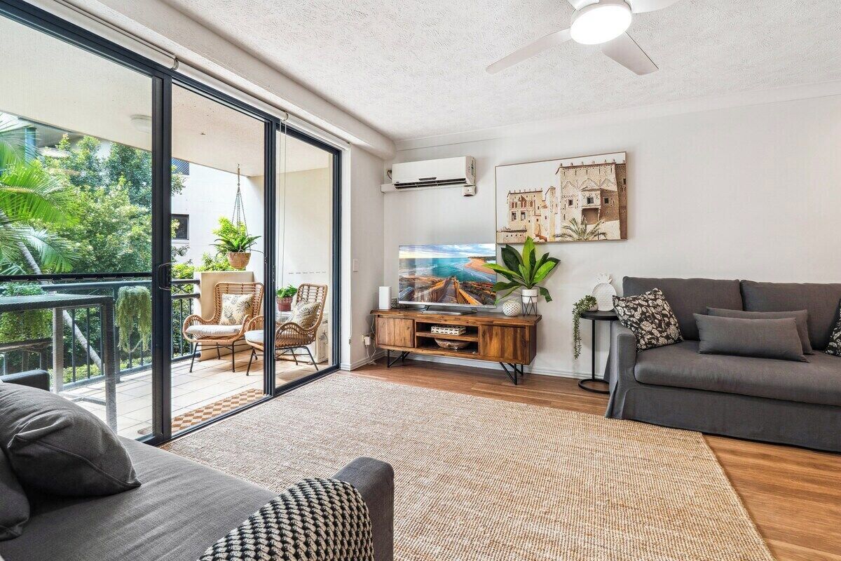 Een moderne woonkamer met een bank, een televisie en een balkon met tuinmeubilair.