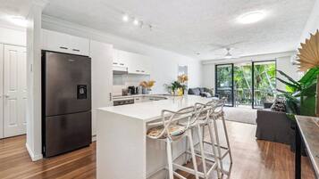 A modern kitchen with a central island, bar stools, and a large refrigerator.