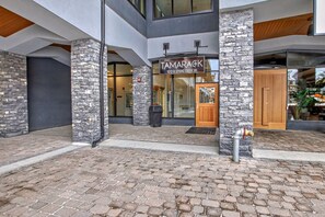 A modern building with a stone facade, a sign reading 'The Tamarack 1012-B Spring Creek Dr', and a fire hydrant on the ground. - Spring Creek Getaway, Luxury 1BR Condo in Canmore (Canmore)