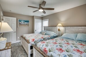 Een slaapkamer met twee bedden, een plafondventilator, een schilderij en een lamp.