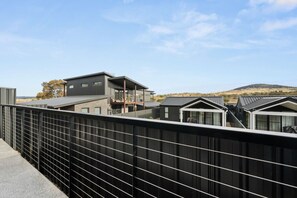 A modern residential area with multiple houses, a metal fence, and a clear sky. - Premium 3BR Snowy Mountains Retreat w/ Ducted A/C! (Jindabyne)