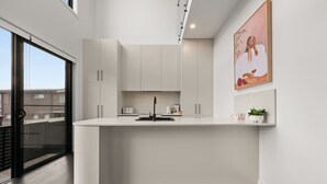 Una cucina moderna con mobili bianchi, un rubinetto nero e un piccolo ripiano.