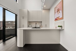 Eine moderne Küche mit weißen Schränken, einem schwarzen Wasserhahn und einer kleinen Arbeitsfläche.