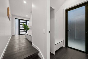 Ein modernes Interieur mit einer Holztreppe, einer Glastür und einer Pflanze.