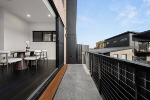 En moderne balkon med spiseplads, en trappe og udsigt til omkringliggende bygninger.