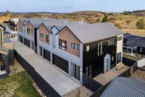 A modern residential building with a flat roof, large windows, and a covered outdoor area. - Premium 3BR Snowy Mountains Retreat w/ Ducted A/C! (Jindabyne)