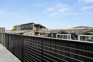 A modern residential area with multiple houses, a metal fence, and a clear sky. - Premium 3BR Snowy Mountains Retreat w/ Ducted A/C! (Jindabyne)