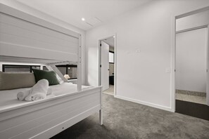 Ein Schlafzimmer mit einem Etagenbett, einem begehbaren Kleiderschrank und einer Tür zu einem weiteren Raum.