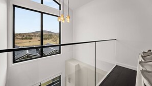 Un interno moderno con un'ampia finestra, una ringhiera in vetro e vista sul paesaggio.
