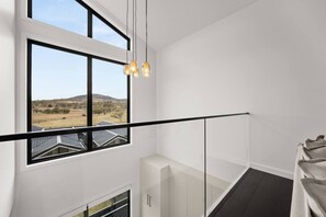 Ein modernes Interieur mit einem großen Fenster, einer Glasreling und Blick auf eine Landschaft.