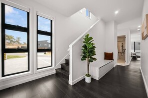A modern interior with a staircase, a potted plant, and a glimpse of a bathroom. - Snowy Mountains Retreat with Indoor Fireplace (Jindabyne)