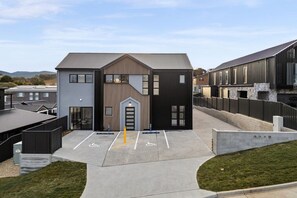 Un bâtiment moderne doté d’une entrée principale, de places de stationnement et d’une clôture périphérique.
