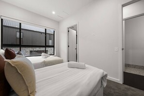Une chambre d’hôtel avec deux lits, une grande fenêtre et une porte donnant sur une autre pièce.