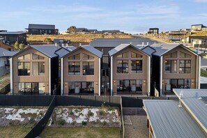 Un edifici residencial modern amb un disseny simètric, grans finestres i un terrat pla.