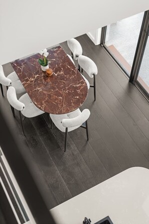 A modern dining area with a marble table and white upholstered chairs.